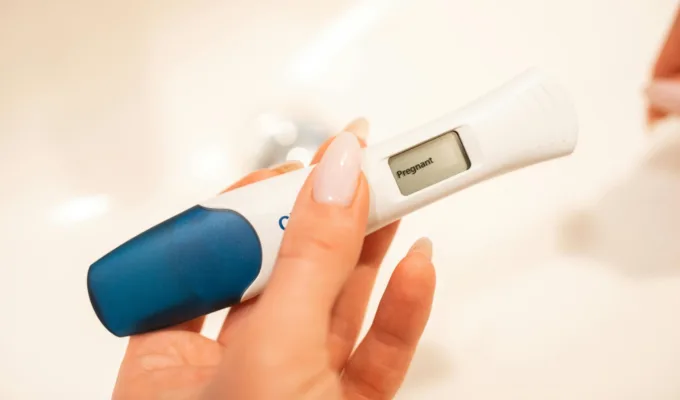 Close-up of a woman holding a positive pregnancy test