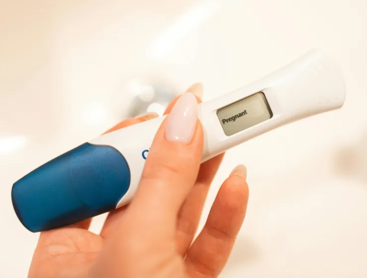 Close-up of a woman holding a positive pregnancy test