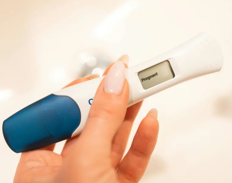 Close-up of a woman holding a positive pregnancy test