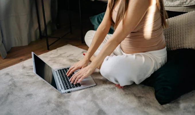 Pregnant woman typing on a laptop.