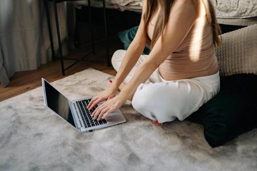 Pregnant woman typing on a laptop.
