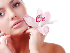 face of beautiful young woman with delicate orchid